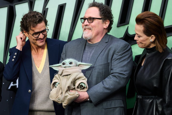 Pedro Pascal, Sigourney Weaver and Jon Favreau (with Grogu) at a The Mandalorian And Grogu fan event in London earlier this month