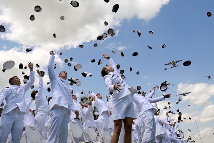 New ensigns toss their caps in celebration at the conclusion of commencement exercises.