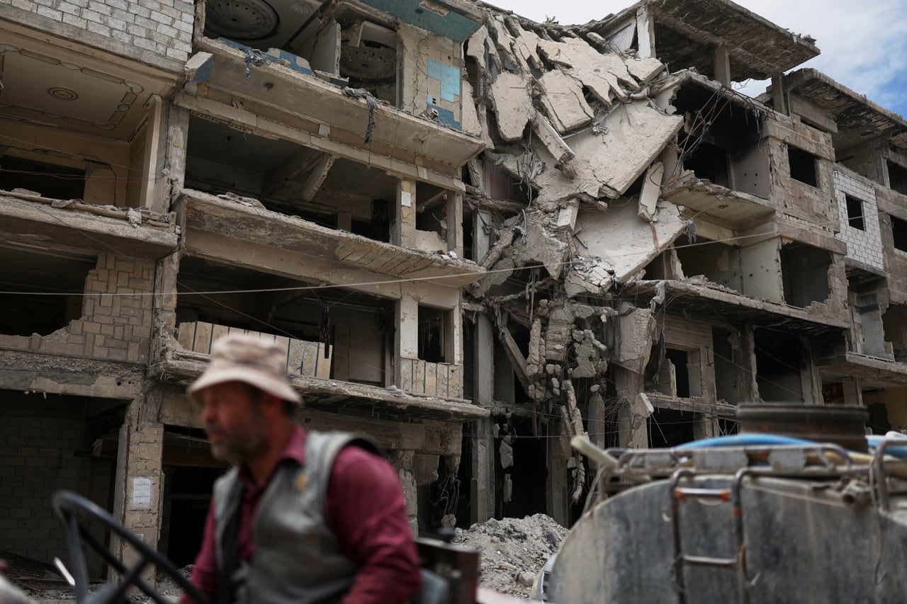 A worker drives a truck past a damaged building in the Yarmouk camp area, home to Palestinian refugees and devastated by years of fighting and displacement during the Syrian war, in Damascus, Syria. Some 6.2 million people are internally displaced in Syria, with more than a million of them living in makeshift camps, according to UNICEF.