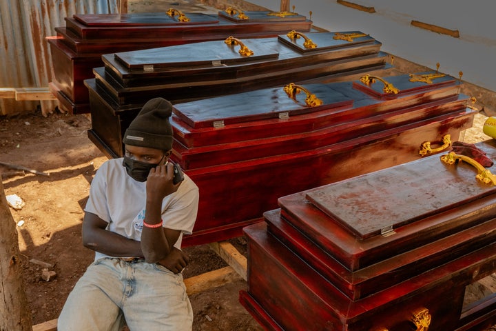 Djakisa Christian, 18, a funeral home director, sits in front of coffins for sale at his shop in Bunia, Congo, Friday, May 22, 2026. (AP Photo/Moses Sawasawa)