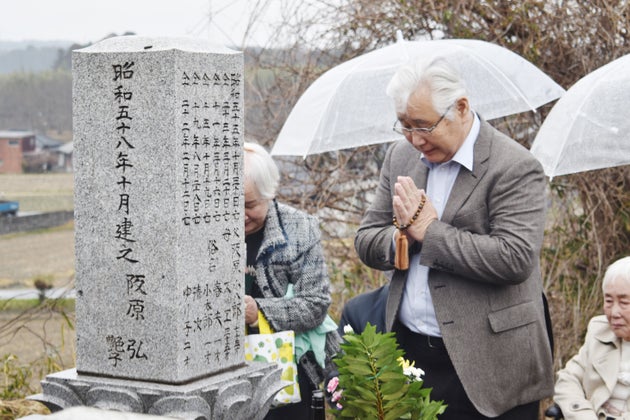 阪原弘さんの墓前に報告する長男の弘次さん（中央）ら