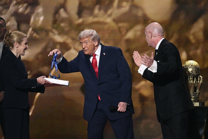 Trump, center, picks up a medal as Infantino, right, applauds him while awarding the commander-in-chief the FIFA Peace Prize during a World Cup draw event at the Kennedy Center in December.
