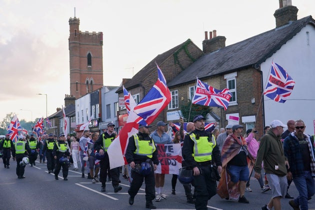 Police officers escort anti-migrant protesters near the Bell Hotel in Epping, London, Sunday, Aug. 31, 2025