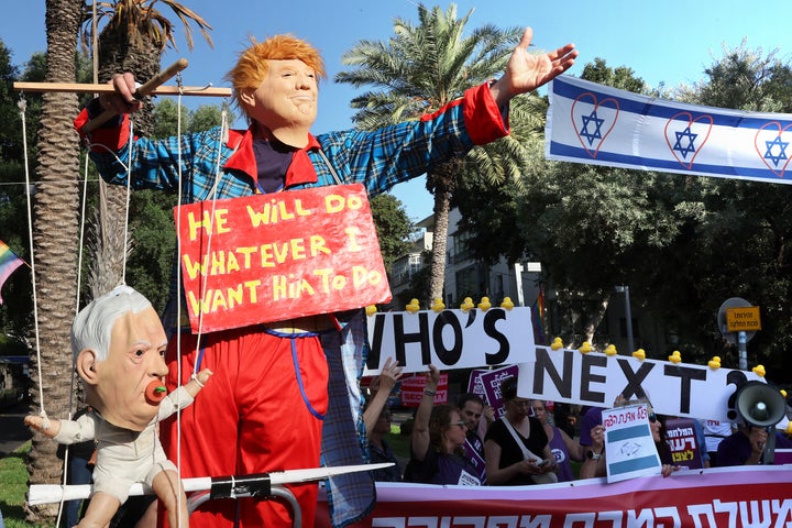A demonstrator dressed as President Donald Trump and holding a puppet depicting Israeli Prime Minister Benjamin Netanyahu as a baby poses at a protest outside the Likud Party headquarters in Tel Aviv on June 4, 2026. Israeli protesters are calling for a political process to end the fighting in Iran and Lebanon, and to restore security for residents and soldiers in the north.