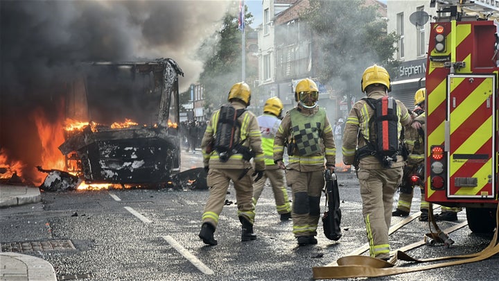 Emergency services attend to a Glider bus, set on fire by protesters, on the Newtownards Road in east Belfast, as disorder flared during an anti-immigration demonstration organized in response to Monday night's stabbing attack in the city.