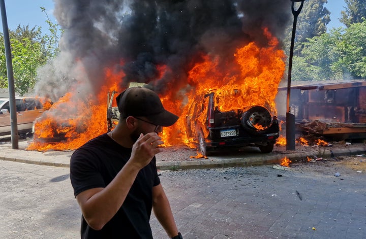 A man passes in front of burned cars that were attacked in an Israeli airstrike in the southern port city of Sidon, Lebanon, on June 10, 2026.