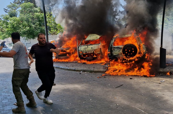 A man runs past burning cars following an Israeli airstrike in the southern port city of Sidon, Lebanon, on June 10, 2026. A senior Iranian source told Reuters that the memorandum between Tehran and Washington would waive sanctions on Iran's oil, unfreeze billions of dollars of its funds, and require a cessation of hostilities on all fronts, including in Lebanon.