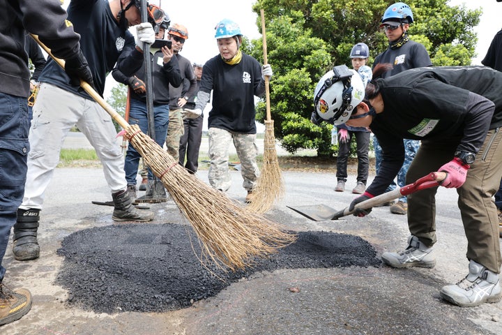 参加者に路面補修の方法を教える豊角純子さん(中央)