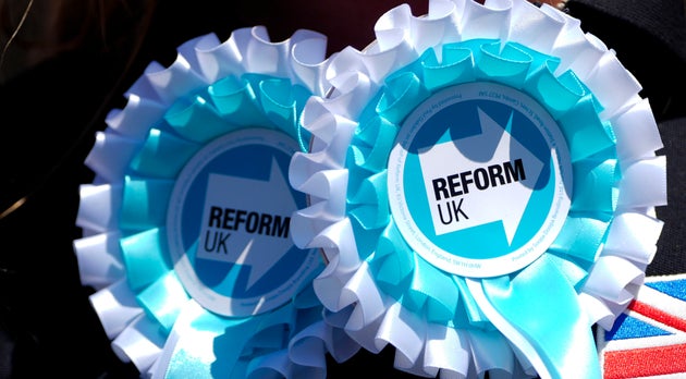 A Reform UK party supporter wears rosettes outside the party office in Clacton-On-Sea, England, Friday, June 21, 2024. 
