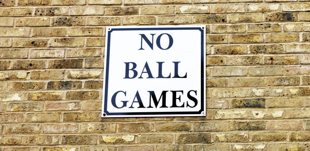 'No ball games' sign on brick wall