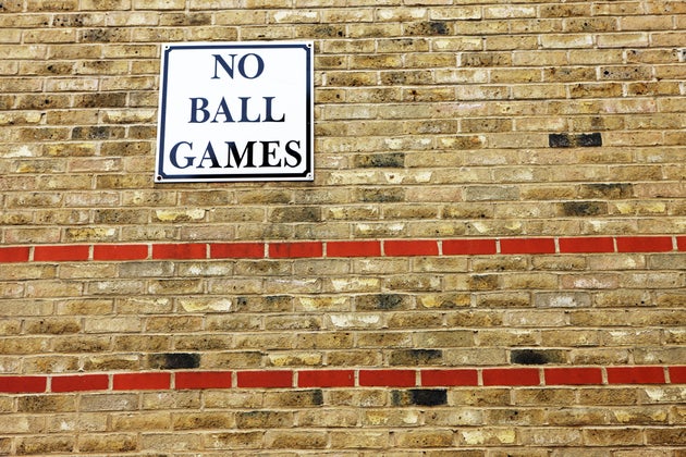'No ball games' sign on brick wall