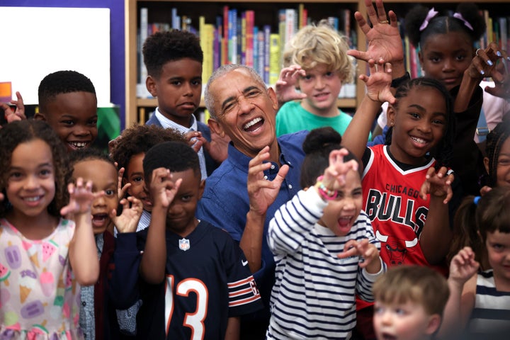 Former President Barack Obama poses for photographs after reading to school children on Friday.