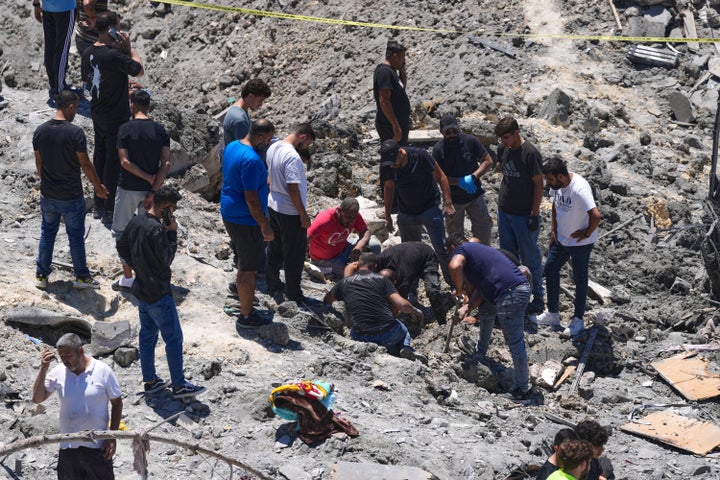 Rescue workers and people search for victims under the rubble of a destroyed building that was hit in an Israeli airstrike in Qannarit village, southern Lebanon, Saturday, June 20, 2026. (AP Photo/Mohammed Zaatari)