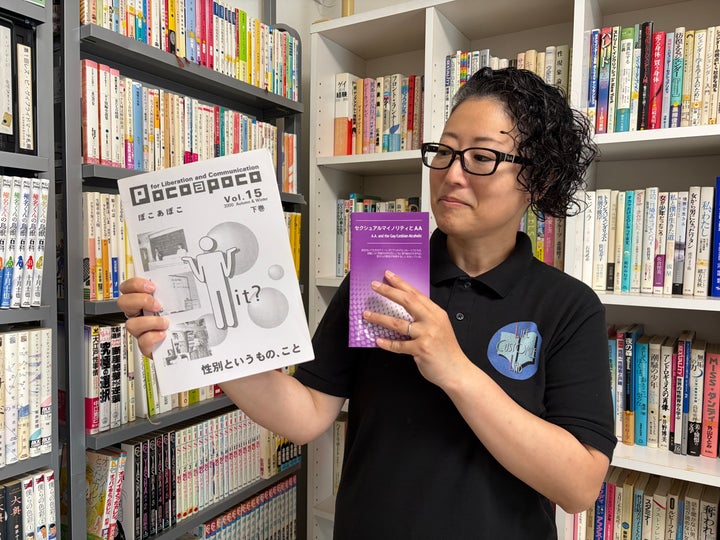 今さんが手にしている紫の資料は、自身が通ったセクシャルマイノリティ専用のAA（アルコール依存症から回復するためのプログラム）のパンフレット。