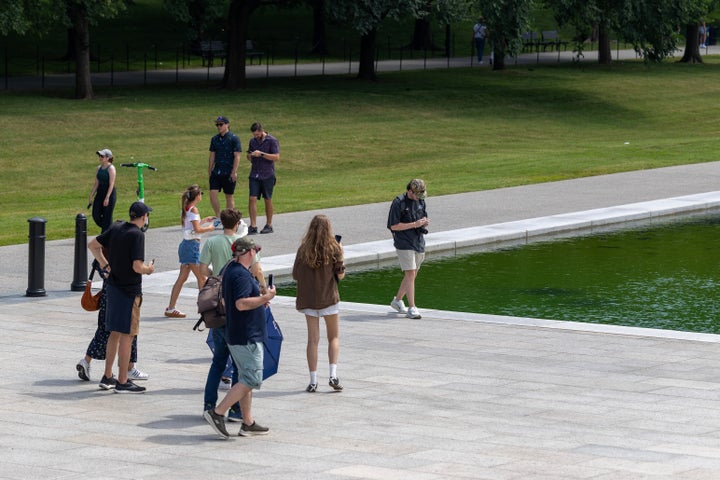 People walk along the Lincoln Memorial Reflecting Pool where algae has begun to bloom following the completion of recent renovations on June 14, 2026 in Washington, DC.