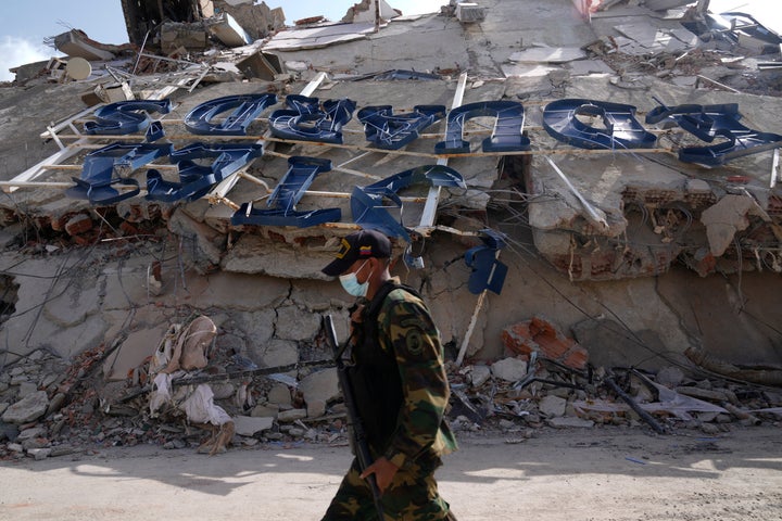 A soldier walks past by the collapsed Hotel Eduard's in La Guaira, Venezuela, Friday, June 26, 2026, two days after twin earthquakes struck the country. (AP Photo/Ariana Cubillos)