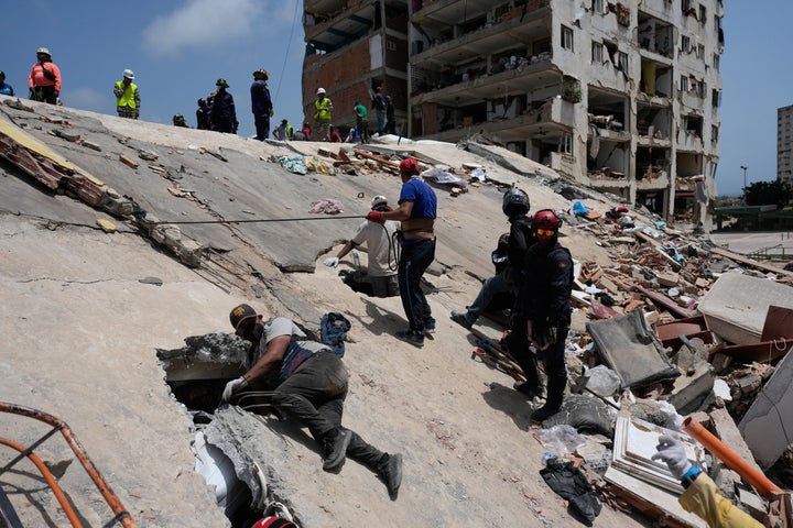 Residents and rescue workers search for survivors in Catia aa Mar, Venezuela, Friday, June 26, 2026, two days after twin earthquakes struck the country. (AP Photo/Fernando Vergara)