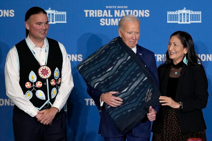 Interior Secretary Deb Haaland, right, and Bryan Newland, Assistant Secretary for Indian Affairs at the Department of the Interior, left, present President Joe Biden with an Eighth Generation blanket from a tribally-owned business, embroidered with "Joe Biden Champion for Indian Country," at the 2024 White House Tribal Nations Summit at the Department of the Interior in Washington, Monday, Dec. 9, 2024. 