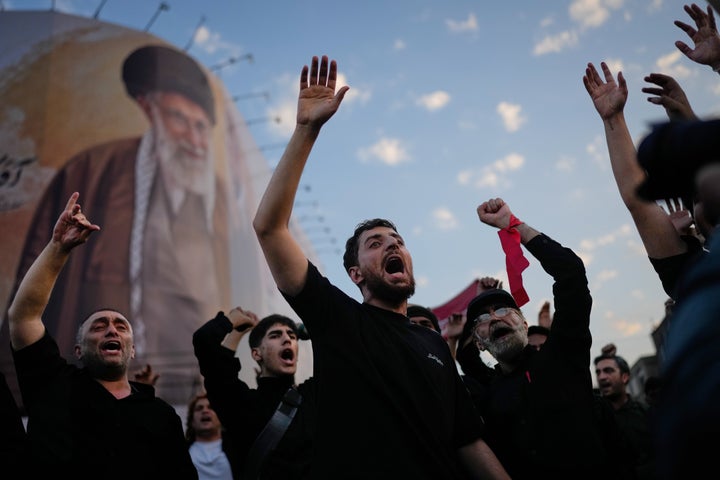 Mourners chant slogans while gathered in Islamic Revolution Square for the funeral procession of the slain Iranian Supreme Leader Ayatollah Ali Khamenei beneath a billboard depicting Khamenei in Tehran, Iran, on July 6, 2026.