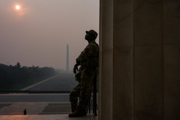 National Guardsmen patrol the Lincoln Memorial as the sun, obscured by wildfire smoke, rises above the Washington Monument and the Reflecting Pool, Friday, July 17, 2026, on the National Mall in Washington. (AP Photo/Julia Demaree Nikhinson)
