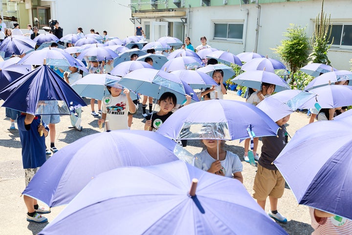 「こども気温 教室」で日傘の使い方を学ぶ様子