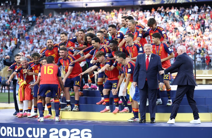 Spain prepares to lift the FIFA World Cup Winner’s Trophy as FIFA President Gianni Infantino directs a seemingly oblivious U.S. President Donald Trump.