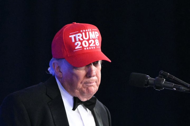 President Donald Trump shows off a "Trump 2028" hat while speaking at the 2026 White House Correspondents' Association Dinner on July 24, 2026.