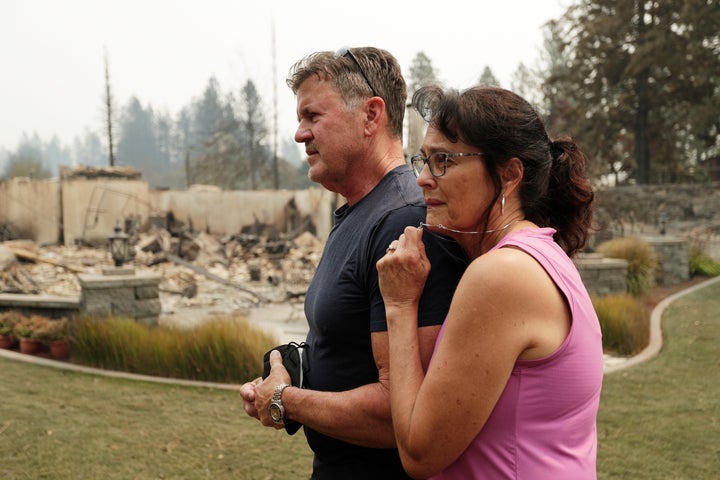 Dan Munson, left, and his wife Suzi Munson stand in the backyard of their house, which burned in a wildfire in Spokane, Wash. 