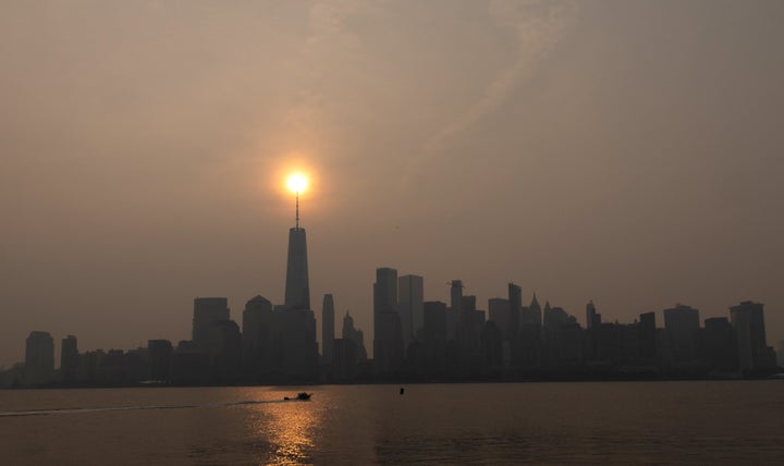 Wildfire smoke from Canada shrouds the sun as it rises behind the skyline of lower Manhattan and One World Trade Center in New York City on July 18.
