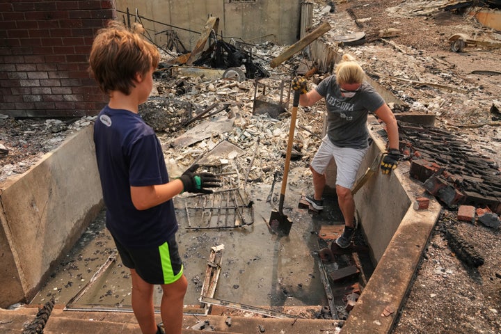 Jana Jensen, right, sifts through the remains of her parents' home with her son Aaren Hartley, 8, after a wildfire hit the northern part of Spokane, Wash., on Aug. 3, 2026. 
