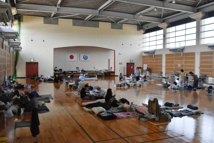 間仕切りなどはない体育館の避難所で、タオルなどを敷いて横になる被災者。この体育館にはエアコンは整備されている=8月3日日午前、熊本県八代市