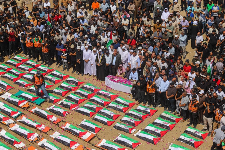 Mourners gather near rows of bodies wrapped in Palestinian flags during a mass funeral procession in the Al-Sabra neighborhood of Gaza City, Gaza Strip, on August 4, 2026. The remains of 112 members of the Abu Sharia and Al-Hasayneh families were recovered from the rubble of their home following an Israeli strike. Relatives stated the attack claimed the lives of more than 300 people. The bodies were buried at Al-Maamadani Cemetery as military operations continue across the territory. (Photo by Ramez Habboub / Middle East Images / AFP via Getty Images)