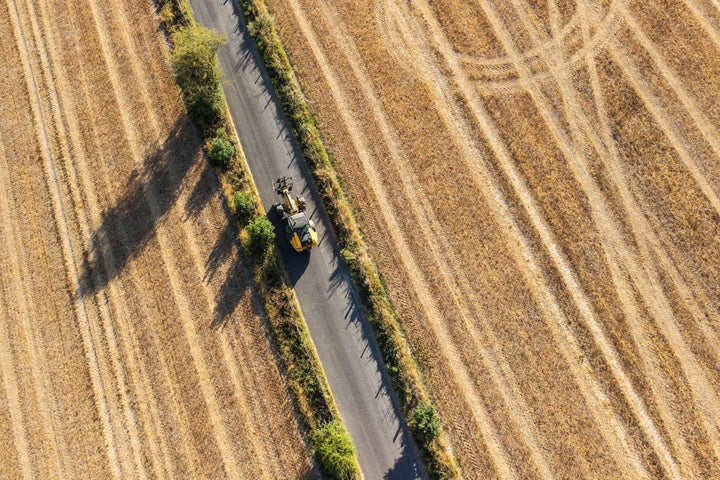 This aerial view shows a vehicle driving down a road with dried out farm fields on either side following months of little or no rain, in the village of Lullingstone, Eynsford, south-east of London on August 6, 2026.