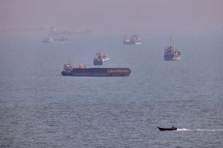 A small boat sails past cargo ships and other commercial vessels anchored in the Strait of Hormuz off Bandar Abbas, Iran, Wednesday, Aug. 5, 2026. (Amirhosein Khorgooi/ISNA via AP)