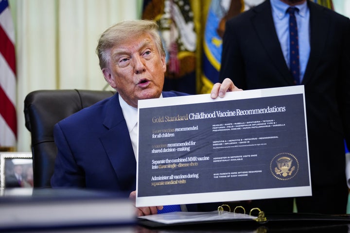 Trump holds a "Gold Standard Childhood Vaccine Recommendations" sign during an executive order signing in the Oval Office on Monday.