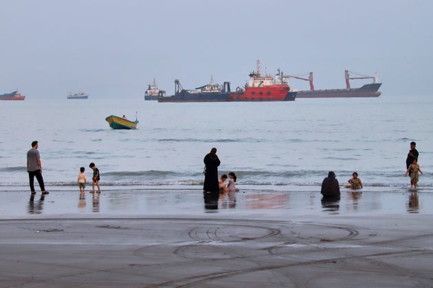 People spend time at a beach as commercial vessels are anchored in the Strait of Hormuz off Bandar Abbas, Iran, on Aug. 5, 2026.