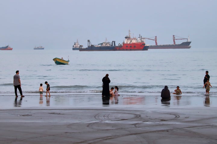 People spend time at a beach as commercial vessels are anchored in the Strait of Hormuz off Bandar Abbas, Iran, on Aug. 5, 2026.