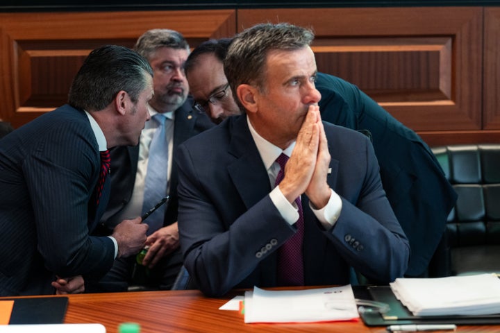 Andy Baker (wearing glasses), directly behind a seated CIA Director John Ratcliffe, consults with Secretary of Defense Pete Hegseth in June 2025.