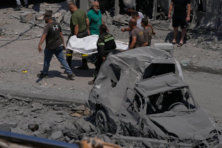 Rescue workers carry the shrouded body of a person who was one of at least 11 killed by an Israeli airstrike in the southern Lebanese village of Deir al-Zahrani, on Aug. 15, 2026.