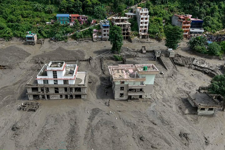 Houses lie partially submerged in muddy water along a riverside after flash floods at Trishuli Bazar in Nepal's Nuwakot district on August 26, 2026. (Photo by Prabin RANABHAT / AFP via Getty Images)