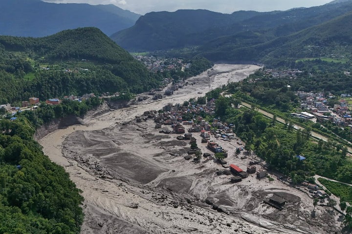 Damaged houses stand precariously near the swollen, debris-choked banks of the Trishuli River after flash floods in Nepal's Nuwakot district on Wednesday, Aug. 26, 2026. (AP Photo/Niranjan Shrestha)