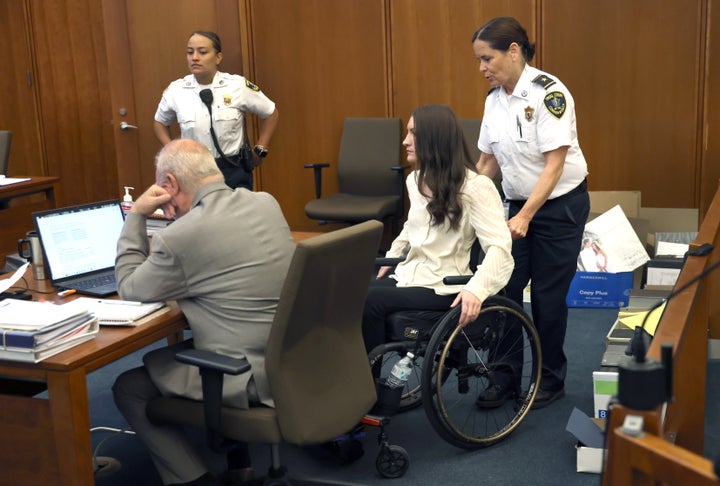 Lindsay Clancy, paralyzed from her suicide attempt, is helped to her seat at Plymouth Superior Court on Aug. 5.