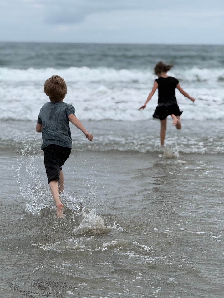 The author’s children run to the ocean while she photographs them.