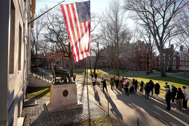 People take photos near a John Harvard statue, left, on the Harvard University campus, Jan. 2, 2024, in Cambridge, Mass. (AP Photo/Steven Senne, File)