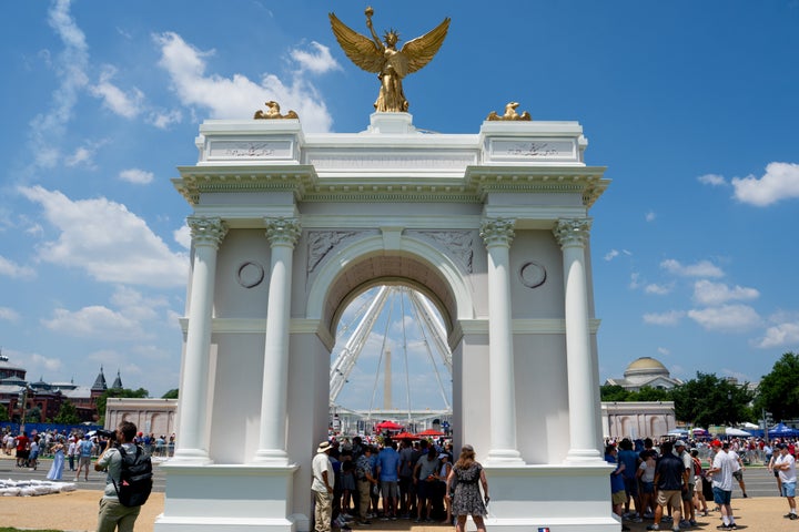 Visitors in July stand in shade under a replica of President Donald Trump's planned Triumphal Arch during the Great American State Fair on the National Mall in Washington, D.C.