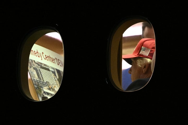 One of several shots of President Donald Trump seen Wednesday aboard Air Force One looking at a poster with the words “Kennedy Center” and “DEMOLISH” on it after landing at Joint Base Andrews, Maryland.