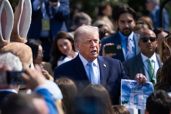 President Donald Trump shows off a rendering of his proposed Triumphal Arch while standing next to someone in a bunny costume during the White House Easter Egg Roll in April.