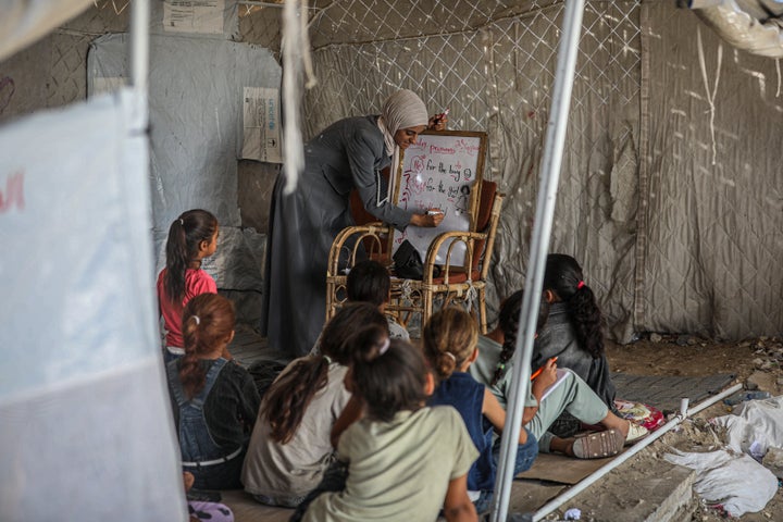 A teacher writes on a makeshift board for Palestinian children inside a temporary classroom tent in western Gaza City, Gaza Strip on September 20.