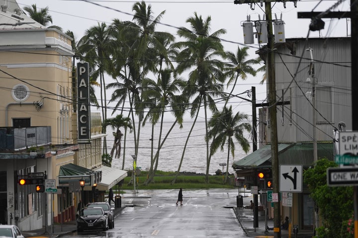 A man crosses the road as Hurricane Nolo sits nearby Saturday, Sept. 26, 2026, in Hilo, Hawaii. (AP Photo/Gregory Bull)