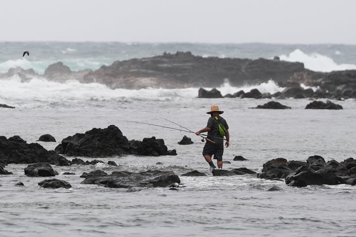 A man walks among rocks while fishing as Hurricane Nolo sits nearby Saturday, Sept. 26, 2026, in Hilo, Hawaii. (AP Photo/Gregory Bull)